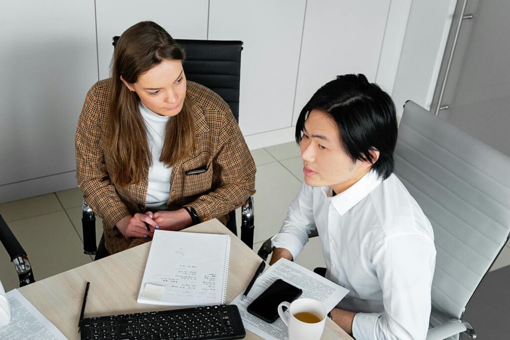 Korean business terms study notes and dictionary on a desk