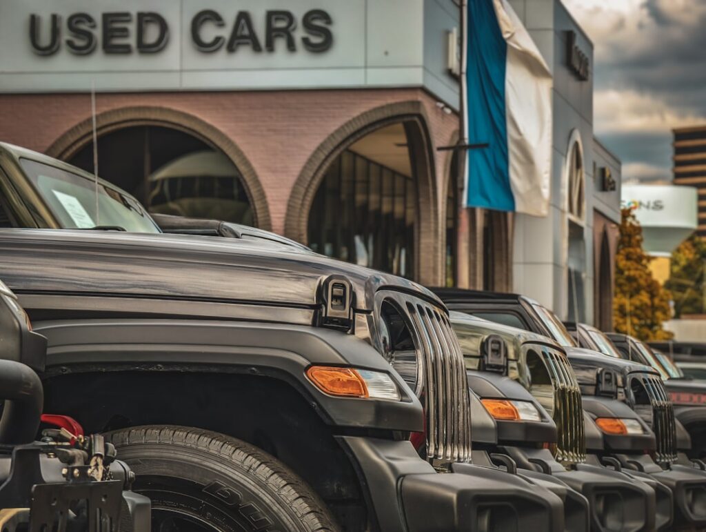 Used car vs new car comparison — view of a used car dealership lot