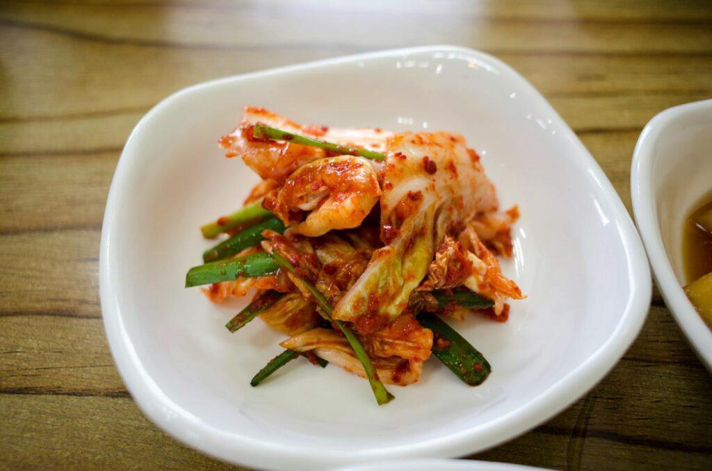 Korean food basics kimchi - a plate of fermenting napa cabbage kimchi